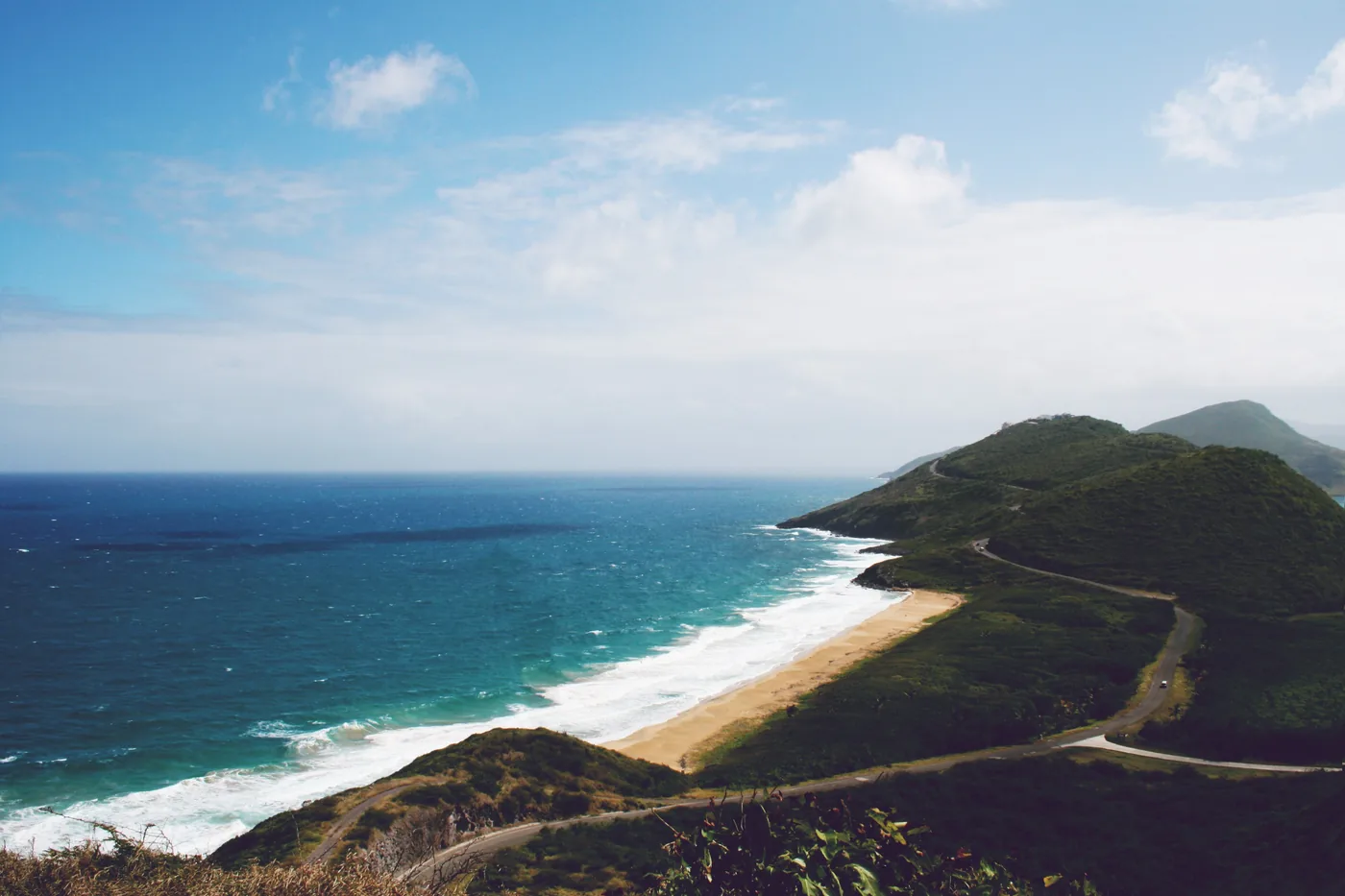 A beach and a green headland on the coast of St Kitts